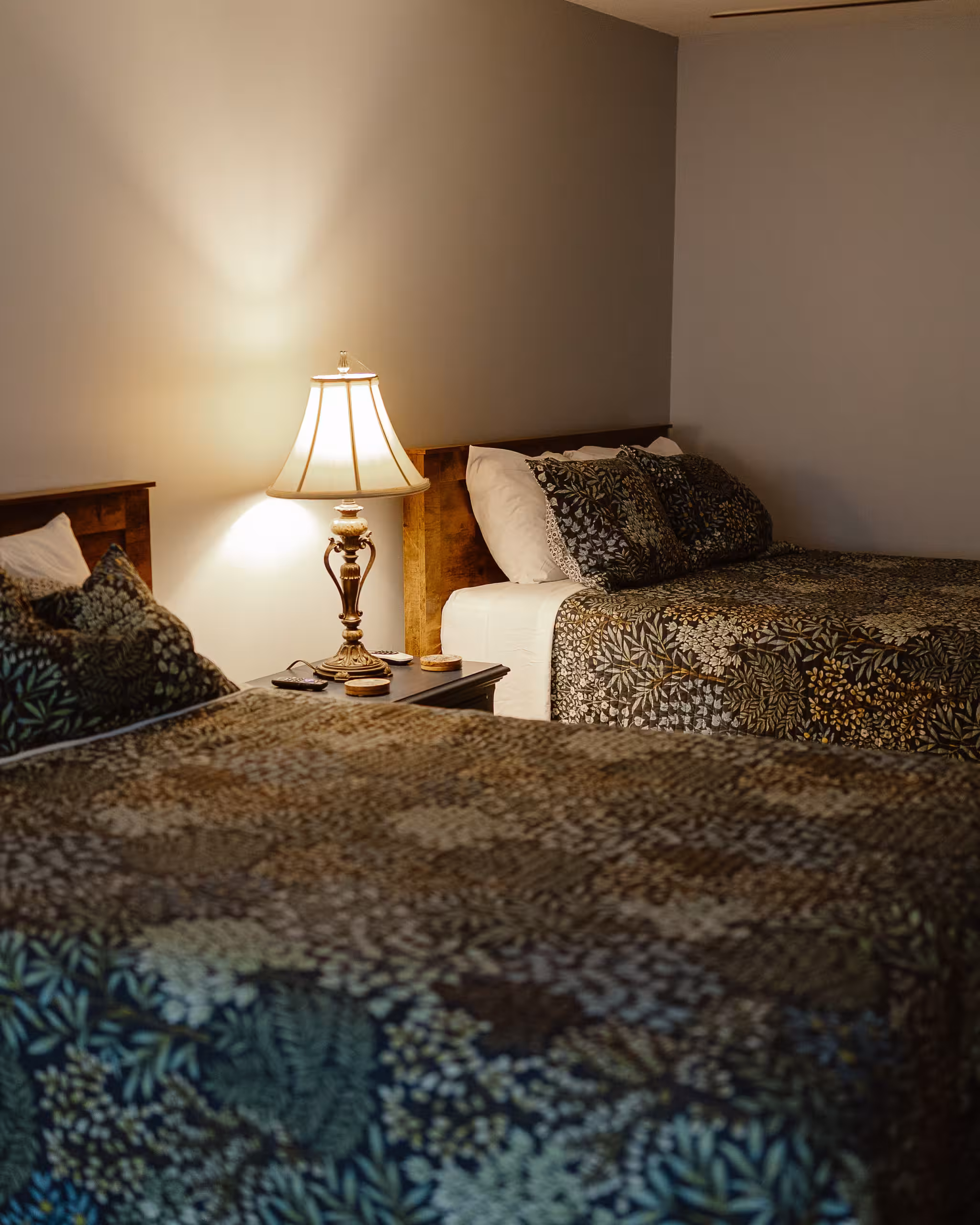 The Cheoah Suite, two beds with patterned quilts and a lamp lit between them