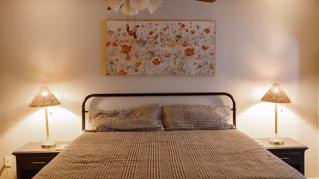 A guest room at Blue Boar Inn in the evening, lamps lit either side of an iron bed